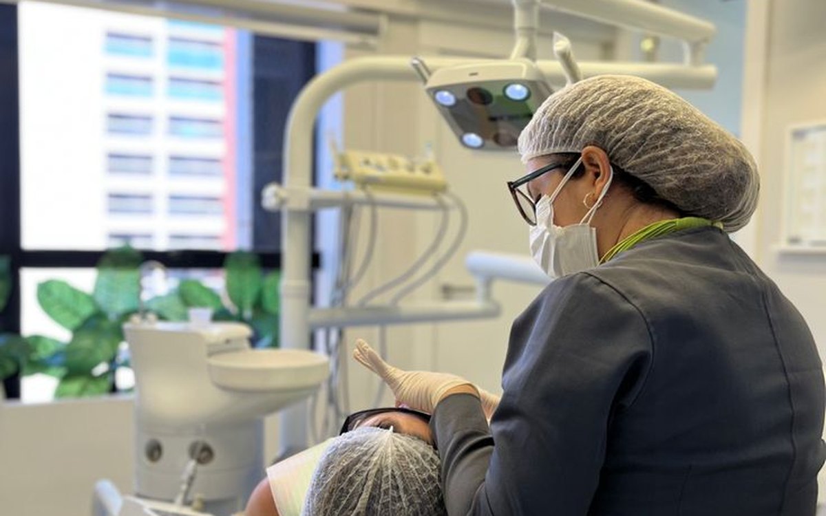 Cirurgiã-dentista atende paciente em consultório odontológico.