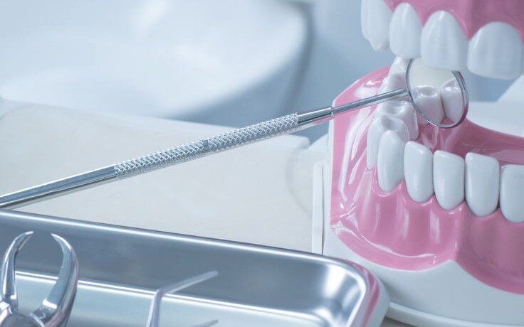 Ilustração de atendimento odontológico com instrumentos e modelo de arcada dentária